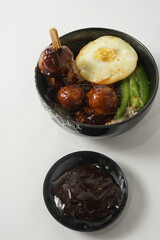 homemade fried rice with sunny side up, vegetables, and delicious grilled meatballs satay, served with traditional condiment of the fermented fish or shrimp.