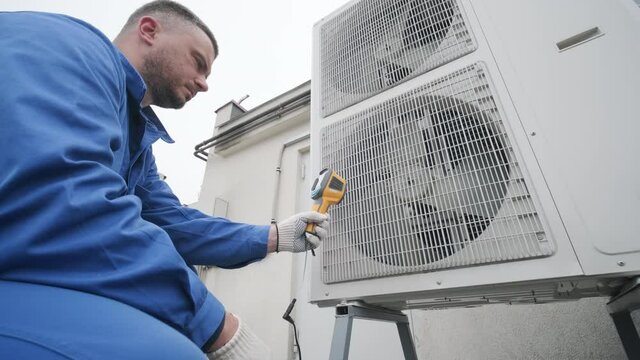 Technician uses a thermal imaging infrared thermometer to check the condensing unit heat exchanger