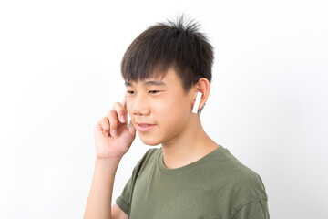 joyful Asian boy 10-12y wearing earpods smiling on white background.
