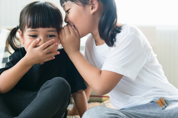Fototapeta na wymiar happy little Asian siblings sharing secrets