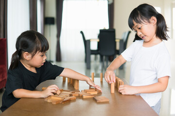two Asian girl playing wooden stacks at home