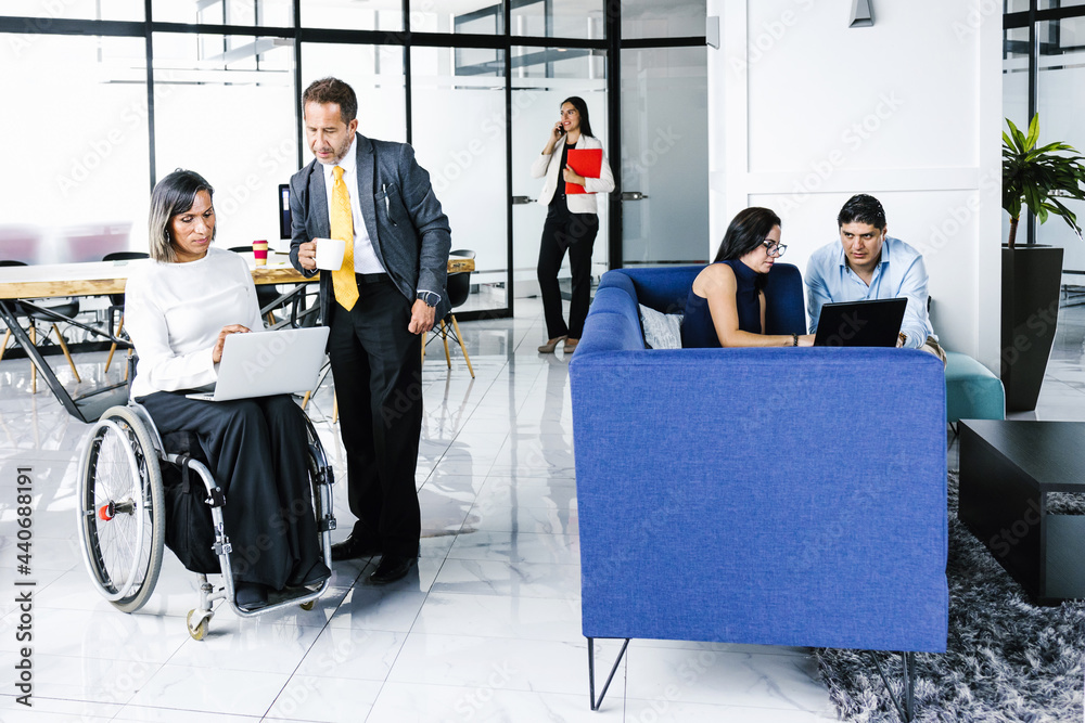 Wall mural group of latin teamwork and transgender woman in wheelchair developing business strategies in office