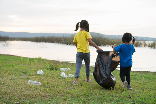 Cute girl while helping sibling to clean up garbage - Powered by Adobe