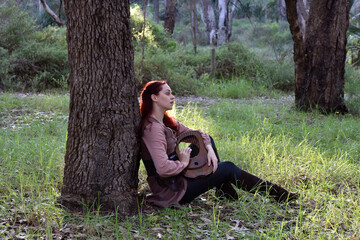 portrait of red haired girl wearing fantasy medieval clothes of a wandering adventurer.  natural light in a woodland forest setting.