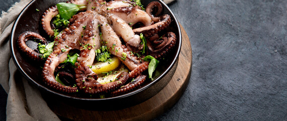 Grilled octopus served with spices and lemon on gray background. Seafood concept.