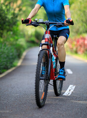 Woman cycling on tropical park trail in summer