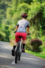 Woman cycling on tropical park trail in summer