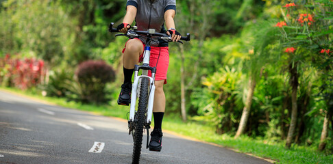 Woman cycling on tropical park trail in summer