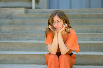 Fototapeta premium Bored woman sitting waiting on steps with thoughtful expression