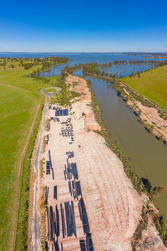 Aerial view of irrigation piping laid out next to a water channel flowing in to a reservoir