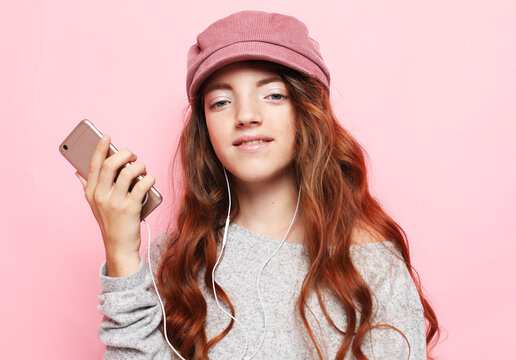 People, technology and internet concept - little girl kid wearing pink hat with smartphone - Powered by Adobe