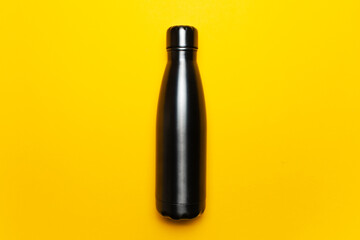 Close-up of black reusable steel thermo bottle for water on background of yellow color.