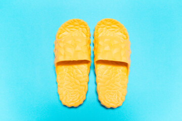 Close-up top view of yellow slippers on background of blue color.