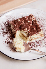 Traditional Tiramisu Cake served on a white plate over wooden background. Italian French cuisine concept