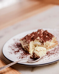Traditional Tiramisu Cake served on a white plate over wooden background. Italian French cuisine concept