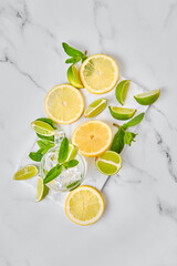 Overhead view of glass with lemon, lime and mint cold lemonade with slices of citrus