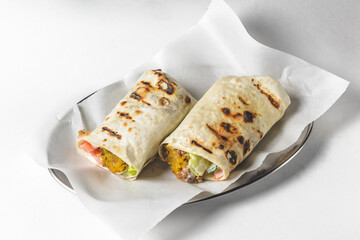 Eastern traditional shawarma served on a metal tray with sauce over white background.