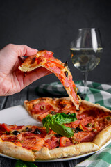 Fresh italian pizza with salami and black olives served with a glass of white wine. Traditional Italian pizza recipe
