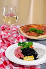 Squid Ink Black Pasta with seafood served on a white plate with a glass of white wine.