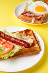Waffle wholesome breakfast. Sour waffles with grilled sausages, fried eggs, delicious sauce and fresh vegetables.