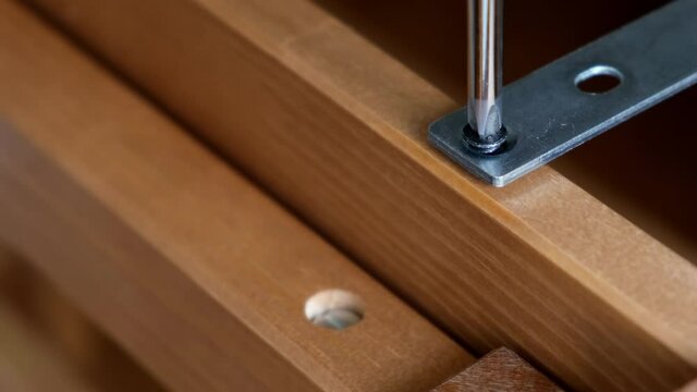 Screws screwed into wood with a screwdriver. Assembling furniture at home.
