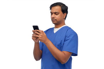 medicine, healthcare and technology concept - indian doctor or male nurse in blue uniform using smartphone over white background