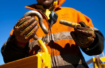 Safety workplace close up image of trained competent rigger high risk worker wearing safety heavy duty glove inspecting D- shape shackle pin prior inserting into crane lifting lug cate during lifting - obrazy, fototapety, plakaty