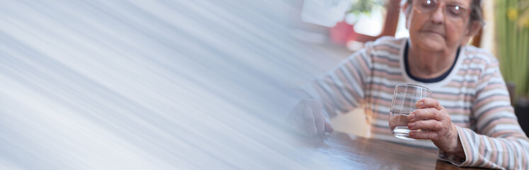 Elderly woman holding a glass of water; panoramic banner