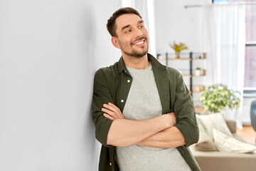 home improvement and decoration and people concept - happy smiling man with crossed arms standing at wall