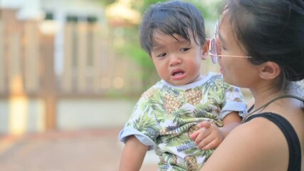 Portrait of 1 year 7 months baby boy crying with mother while she holds him and tries to comfort him.