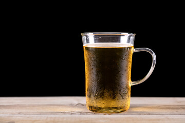 A glass of cold beer in front of a black background