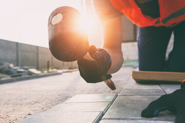 Worker lining paving slabs path