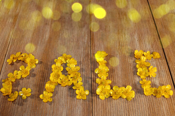  beautiful inscription sale, laid out of buttercup flowers on a wooden background