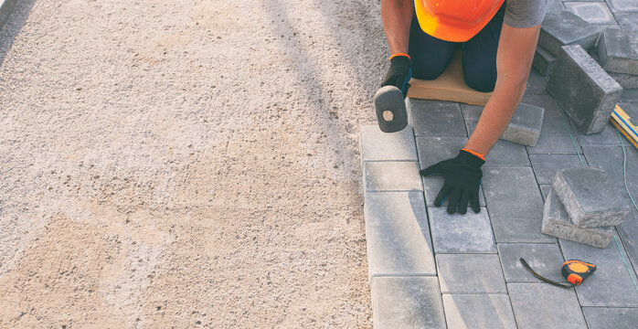 Worker lining paving slabs path