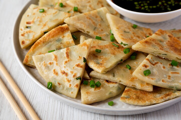 Homemade Scallion Pancakes with Soy Dipping Sauce on a white wooden background, side view. Close-up.