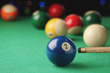 Billiard ball with number 2 and cue on green table
