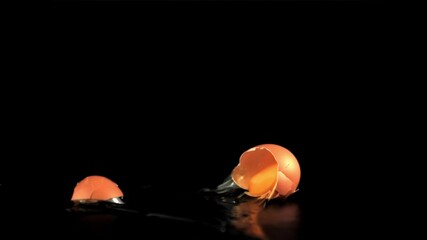 Super slow motion raw egg falls on the table and breaks. On a black background. Filmed on a high-speed camera at 1000 fps. - Powered by Adobe