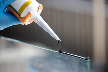 Closeup of silicone glue and a glue gun to tightly stretch aluminum and glass.