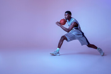 Fototapeta na wymiar Basketball player practicing with ball in studio