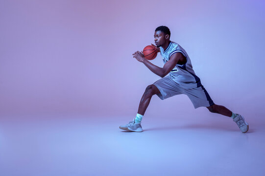 Basketball player practicing with ball in studio