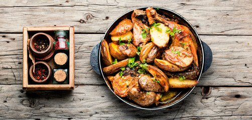 Roast chicken leg with potatoes on iron cast pan