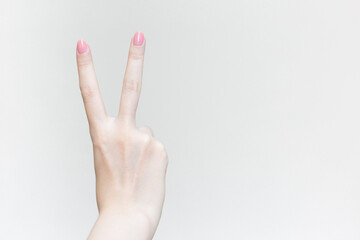 Beautiful female hand shows heart symbol as victory sign in manicure concept.