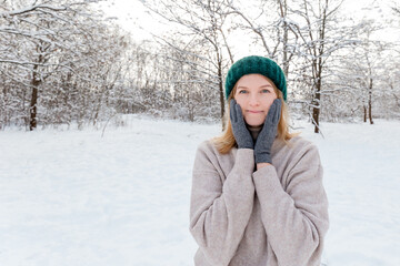Obraz premium Happy young woman wearing in winter knitted hat and sweater posing over nature background, Looking at camera and smile. Travel and active life concept. Outdoors