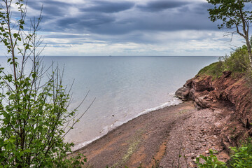 View on a small cove with red sand and clay on the way to the Pointe Aux Corbeaux rock near Paspebiac, Quebec (Canada)