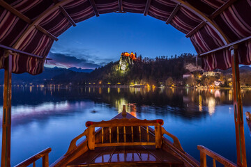 Tourist boat frames the iconic Bled Castle in the evening © seanliew