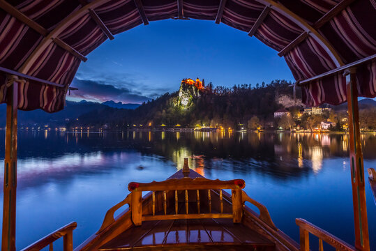Tourist boat frames the iconic Bled Castle in the evening