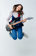 Portrait shot of a cute smiling young Thai-Turkish teenager jumping and holding the electric guitar...