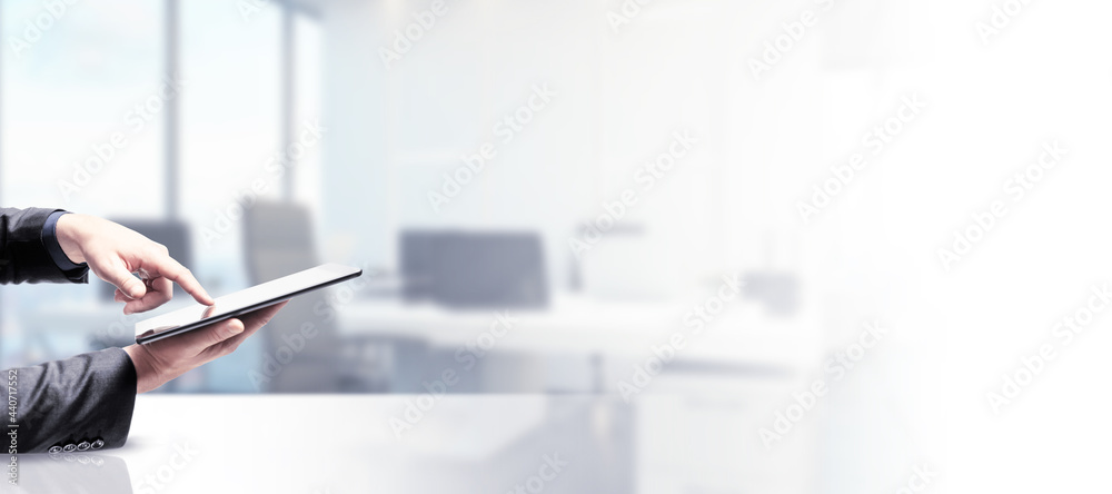 Poster Side view and close up of businessman hand using pad screen on blurry white office background with mock up place. Technology and device concept.