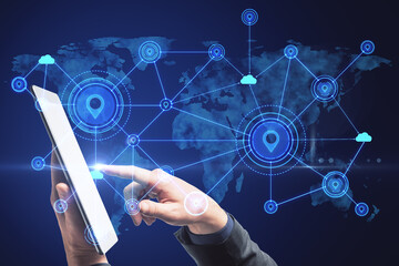 Hand using tablet with abstract map and location pins hologram on blue background. Geolocation and globalization concept.