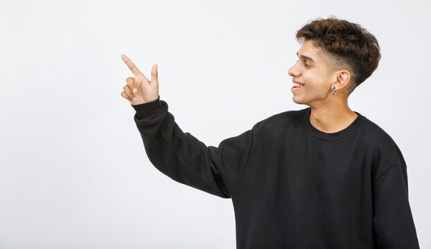 Horizontal portrait shot of a junior boy looking and pointing the finger to copy space at the side of the image with smiling to presenting and showing promoting product isolated on white background
